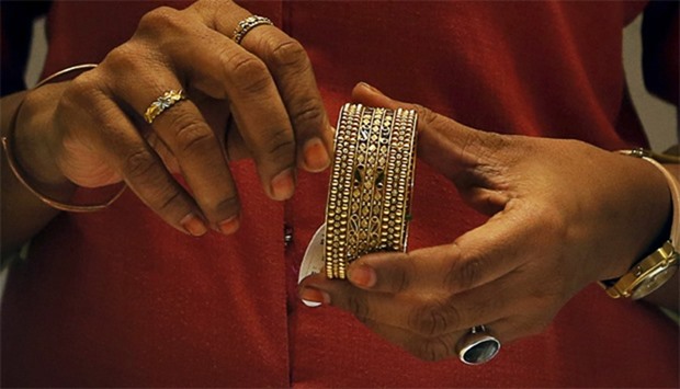 An employee shows a gold bangle to a customer inside a jewellery showroom