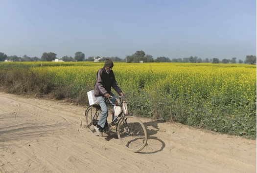 Postman Ratan Lal carries a parcel on his bicycle to be delivered to a customer in a village in the Rajasthan district of Neemrana.