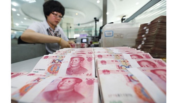 A teller counts yuan banknotes in a bank in China. The yuanu2019s appreciation in the four years through 2013 prompted companies to borrow dollars offshore and use the money to profit from a strong currency and higher interest rates in China.
