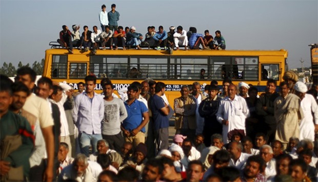 Demonstrators from the Jat community sit on top of a school bus