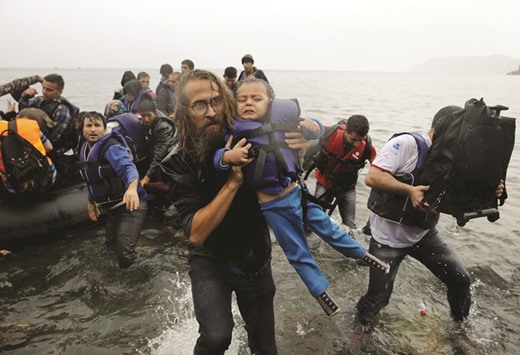 A volunteer carries a Syrian refugee child off an overcrowded dinghy at a beach after the migrants crossed part of the Aegean Sea from Turkey to the Greek island of Lesbos in this September 23, 2015 file photo.
