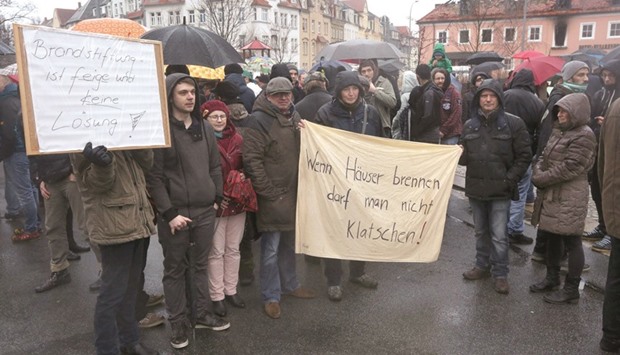 People hold up banners reading u2018Arson is coward and no solutionu2019 (left) and u2018When houses burn one cannot applaudu2019 as they demonstrate in solidarity with refugees in Bautzen, eastern Germany.