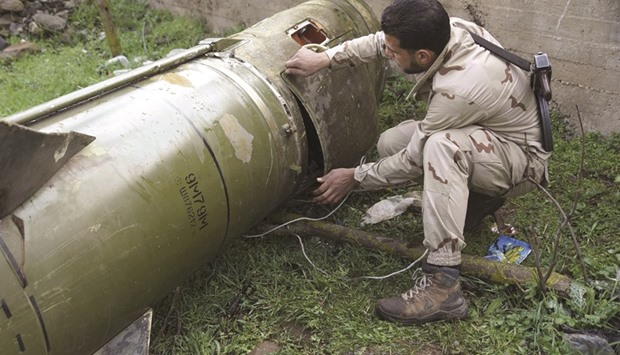 A rebel fighter inspects a piece of a rocket that landed in an area that connects the northern countryside of Deraa and Quneitra, Syria yesterday.