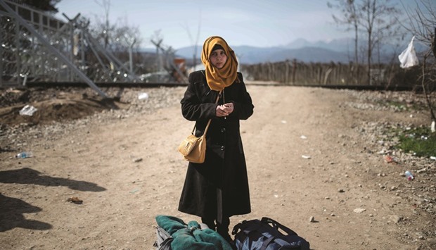 A young migrant stands with her bags after crossing the Greek-Macedonian border near Gevgelija town.