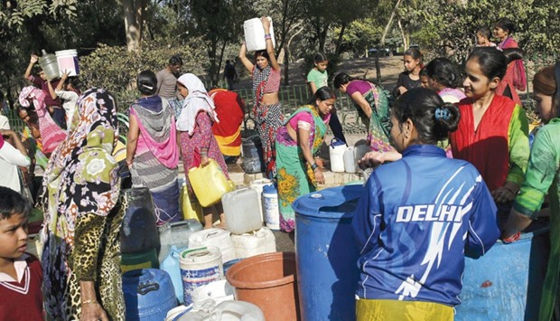 Residents carry water in containers after filling them from a municipal tanker in New Delhi yesterday.