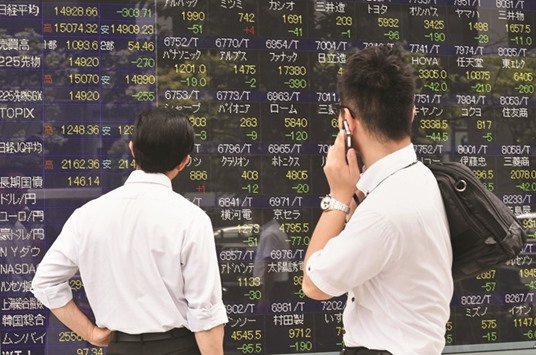 Pedestrians look at a share prices board in Tokyo. The Nikkei 225 closed up 0.93% at 16,290.53 points yesterday.
