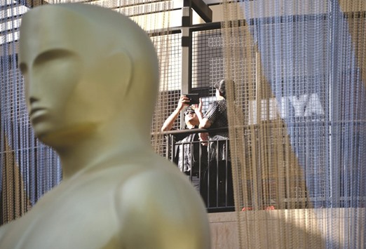 Tourists take photos of a giant Oscar statue at the entrance of Dolby Theatre in Hollywood, California amid continuing preparations for this weekendu2019s 88th Academy Awards.