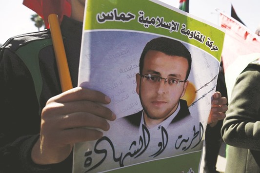 A man holds a poster of Palestinian journalist Mohammad al-Qiq, who was detained by Israel in November and was on a hunger strike to protest his detention without charge, during a rally in support of him, in the West Bank city Ramallah yesterday.