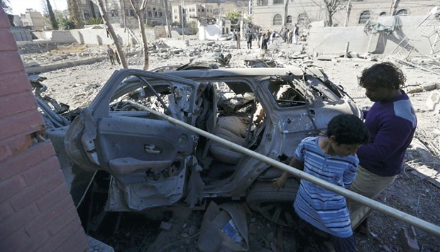 Boys look at a car destroyed by a Saudi-led air strike in Sanaa yesterday.
