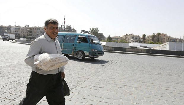 A man carries a bag of bread in central Abbasid Square, next to the Jobar suburb of Damascus.