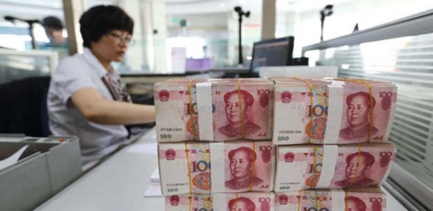Yuan banknotes are placed on a staffu2019s table in a bank in China. The yuan has weakened 5% versus the dollar since a surprise devaluation in August, even as the central bank burnt through more than $400bn of the nationu2019s foreign-exchange reserves over the last six months trying to support the exchange rate amid record capital outflows.
