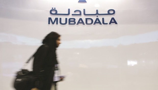 A Mubadala employee walks past the companyu2019s logo at their exhibition booth during the Singapore Airshow in this photo dated February 20, 2008. Abu Dhabi is reviewing its largest state-owned firms as a slump in oil pressures the emirateu2019s finances, people with knowledge of the matter said in November.