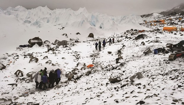 In this file photograph, an injured climber is carried on a makeshift stretcher to a medical tent further down from Nepalu2019s Everest Base camp after an avalanche triggered by an earthquake devastated the camp.