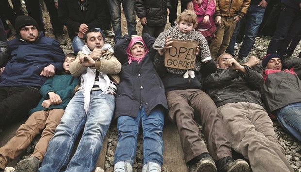 Migrants trapped at the Greek-Macedonian borders lie on the rail tracks leading to Macedonia during their protest demanding the opening of the borders.