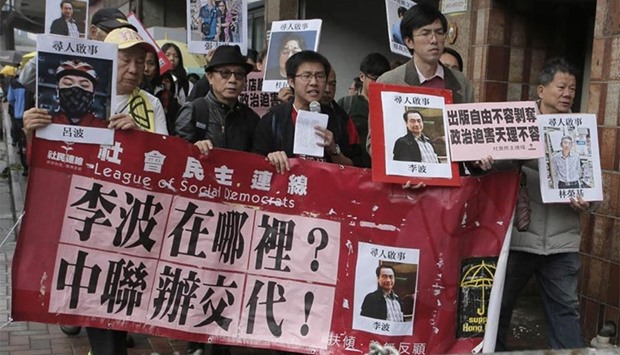 Protesters in Hong Kong hold photos of the missing booksellers