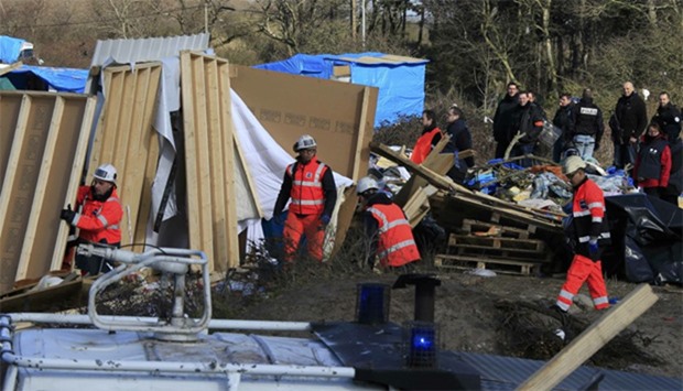 Workmen tear down makeshift shelters during the partial dismantlement of the camp for migrants called the ,jungle,, in Calais