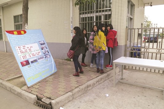 A group of young female migrant workers look for work outside a factory in the Pearl River Delta. The workers were employed on temporary contracts before the Chinese New Year holiday, and had no work to come back after the holiday, forcing them to look for new jobs.
