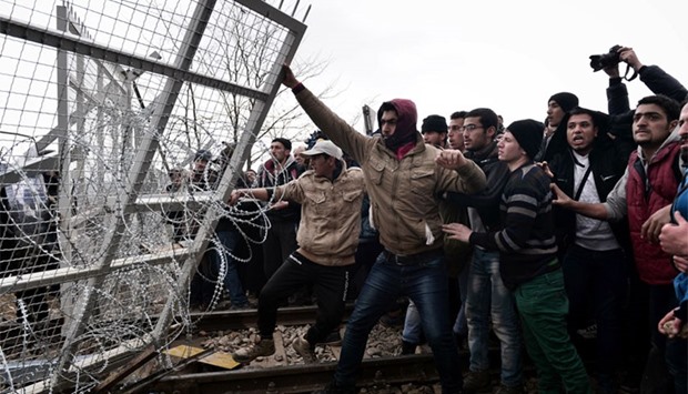 Migrants try to break through a border fence into Macedonia near the Greek village of Idomeni. AFP