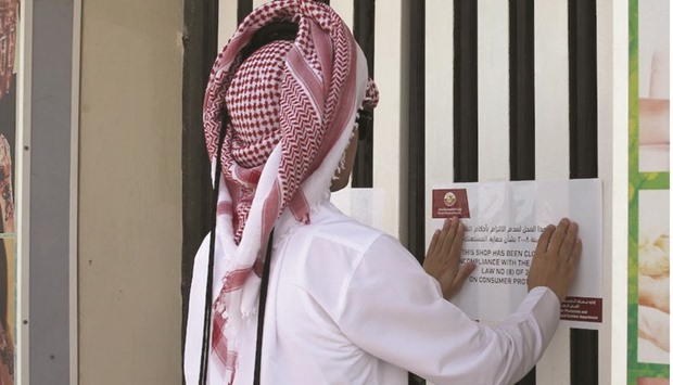 A ministry official pasting a closure notice on the salon door.