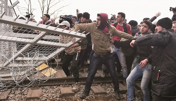 Refugees pull down a fence on the Greek-Macedonian border near the village of Idomeni yesterday.