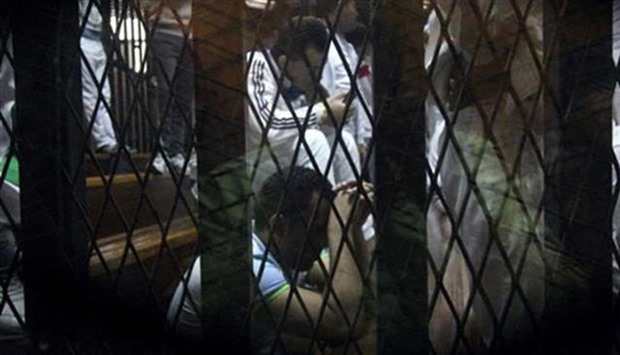 Defendants sit behind bars during their trial in Cairo