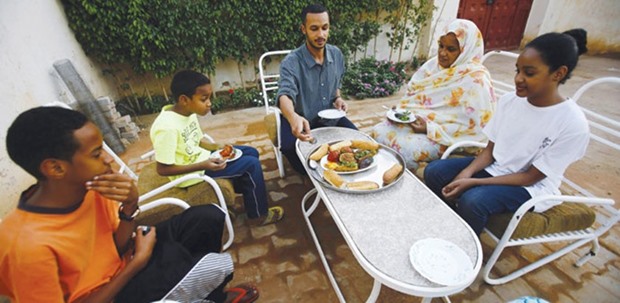 Omer Eltigani, a young British Sudanese pharmacist, and his relatives eat the Sudanese u201cMahshiu201d (stuffed vegetables) that he prepared at his auntu2019s house in Khartoum.