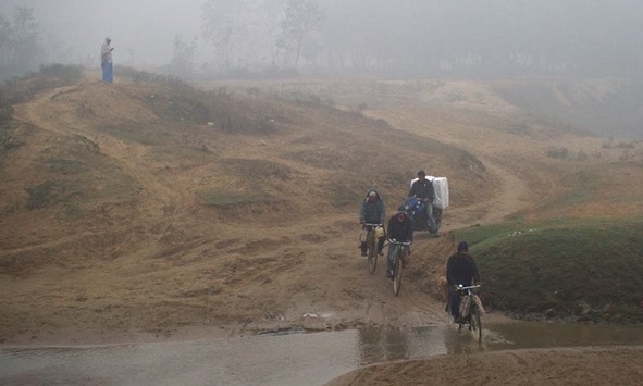 People smuggling fuel on bicycles and scooters cross the small stream that marks a section of Nepalu2019s border with India.
