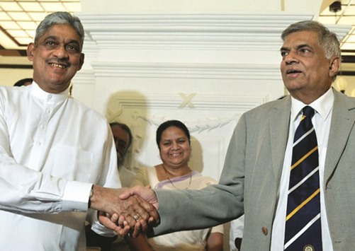 General Sarath Fonseka, left, and Prime Minister Ranil Wickremesinghe shaking hands during an agreement signing ceremony in Colombo yesterday.