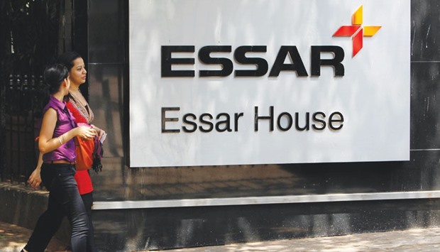Employees walk past an Essar Group logo outside its headquarters in Mumbai. The Indian firm is planning to sell assets after earnings were hurt by a fall in commodity prices, weak demand and lower capacity usage at its businesses.