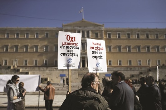 A protesting journalist holds placards during a demonstration against planned pension reforms in front of the parliament building in Athens. The placards read u2018Hands off the pension fundsu2019 and u2018No pension and wage cutsu2019.