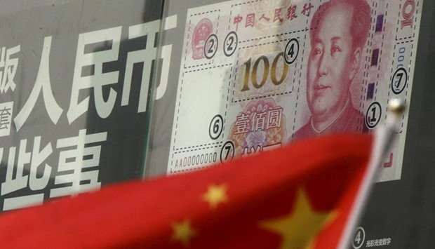 A Chinese national flag is seen in front of a poster explaining the design of the new 100 yuan banknote at a branch of a commercial bank in a business district in Beijing.