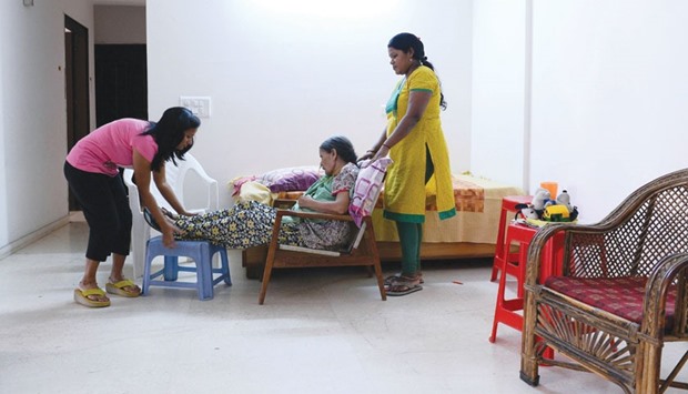 Indian woman Suresh Rani, given an overdose of sodium by doctors at a hospital which resulted a permanent damage to her brain, being helped by her daughter Mamta (left) and an attendant at her home in Noida, near New Delhi.