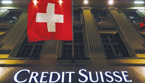 The logo of Swiss bank Credit Suisse is seen below the Swiss national flag at a building in the Federal Square in Bern in this May 15, 2014 file photo. Credit Suisse slumped 10.9% yesterday, the biggest loss in the FTSEurofirst 300 index. The bank posted its first full-year loss since 2008 after it booked a big impairment charge for its investment banking business.