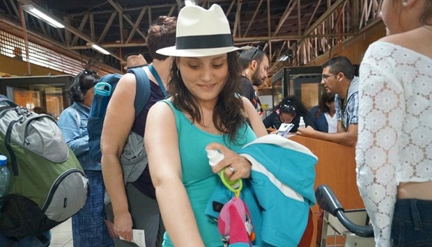 A traveller applies repellent spray on her arm after receiving the spray and information about the Zika virus during a prevention campaign by Chile's Health Ministry at Easter Island airport.