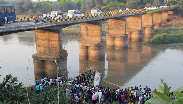 Indian rescue workers and villagers attempt to extract the injured and dead passengers from a Gujarat State Road Transport Corporation passenger bus which plunged into the river Purna near Navsari, some 315 kms from Ahmedabad