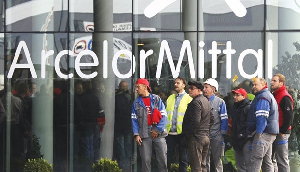 ArcelorMittal steel workers wait outside the companyu2019s regional headquarters in Flemalle, Belgium. The worldu2019s largest steelmaker launched plans yesterday for a $3bn share issue to help reduce debt and cut costs, having been hit by a plunge in steel prices which it blamed on a surge in cheap exports from China.