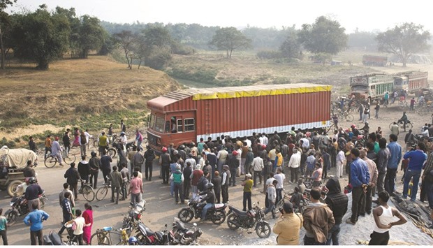 Nepalese and Indian bystanders look on as cargo trucks pass through the India-Nepal border at Birgunj, some 90kms south of Kathmandu, yesterday.
