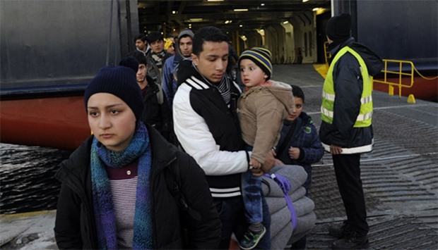 Refugees arrive aboard a passenger ferry