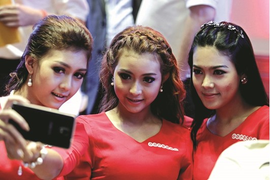 Models take a selfie during the official launch of Ooredoo mobile sim card in Myanmar at the Sule-Shangri-La Hotel, Yangon, Myanmar in this file photo dated August 2, 2014. The financing will support Ooredoou2019s strategy for Myanmar, enabling it to accelerate the reach of its modern telecommunications network for the people of Myanmar, boosting economic growth and job creation across the country.