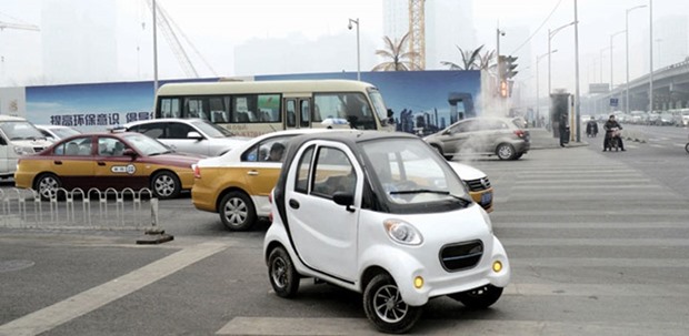 A Chinese-produced electric car being driven along a street on a heavily polluted day in Beijing. Smog-choked cities are fuelling a boom in electric vehicles in China.