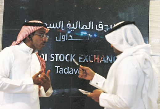 Traders talk as they monitor stock information at the Saudi Stock Exchange (Tadawul) in Riyadh. The kingdom opened its market to direct foreign investment in June last year.