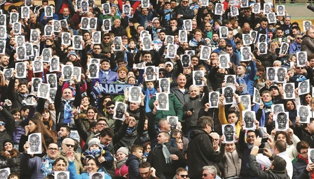 People hold flyers bearing the face of Napoliu2019s French defender Kalidou Koulibaly before the Italian Serie A football match at the San Paolo stadium in Naples yesterday.