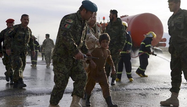 An Afghan National Army officer escorts an injured boy from the site of a suicide attack on the outskirts of Mazar-i-Sharif on Monday.