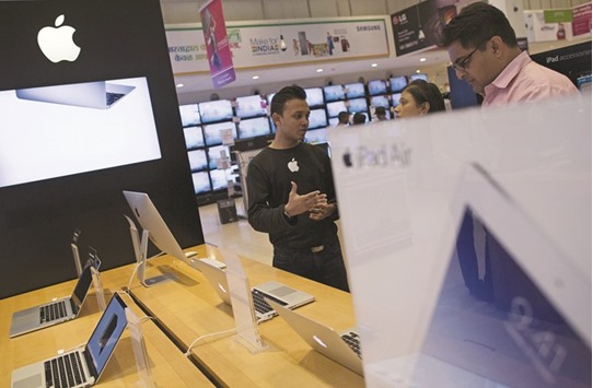 An Apple salesperson speaks to customers at an electronics store in Mumbai. As red-hot sales in China show signs of cooling, the US firmu2019s executives are touting Indiau2019s growing appetite for iPhones.