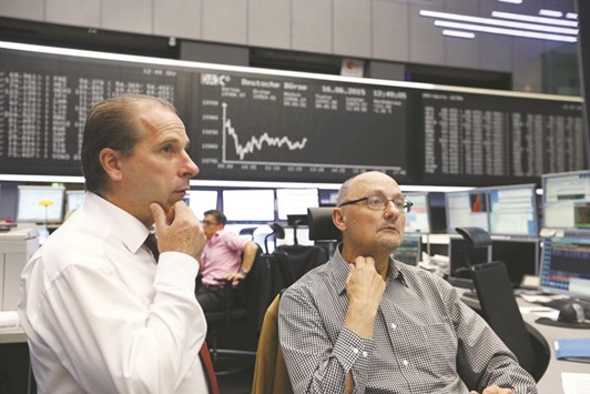 Traders look at the share price index board at the Frankfurt Stock Exchange. The DAX 30 closed down 3.3% at 8,979.36 points yesterday for the first time since October 2014.