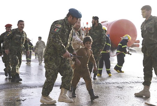 An Afghan Army officer escorts a boy from the site of a suicide attack on the outskirts of Mazar-i-Sharif yesterday.
