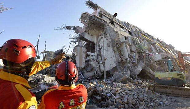 Rescue workers stand next to the remains of the Wei-Kuan complex which collapsed in the southern Taiwanese city of Tainan, on Monday.