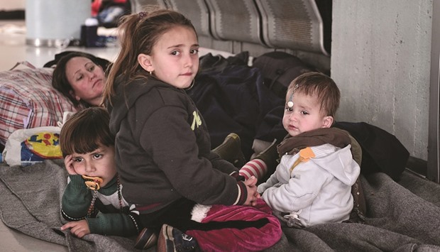 A woman and her children rest in the passenger terminal at the port of Piraeus, near Athens, where dozens of refugee and migrant families live temporarily, prior being able to travel towards the borders.