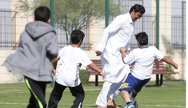 HH the Emir playing football with children.