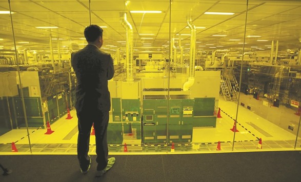 A journalist looks through a glass wall at Japan Displayu2019s new production line for LCD panels, which is lit under yellow safe light, in its factory in Mobara. Innovation Network Corp of Japan is pitching Sharpu2019s board on plans to create a Japanese smart home-appliances giant, as the state-backed fund seeks support for its bailout bid over a rival offer from an overseas bidder, people with knowledge of the matter said.